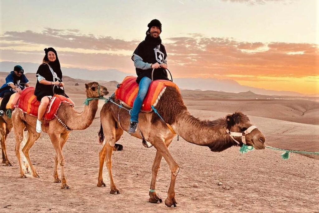 Tourists on a camel caravan experiencing a sunset ride in the Agafay Desert.